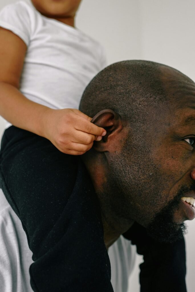 Smiling father carrying child on shoulders, symbolizing family bond and happiness.